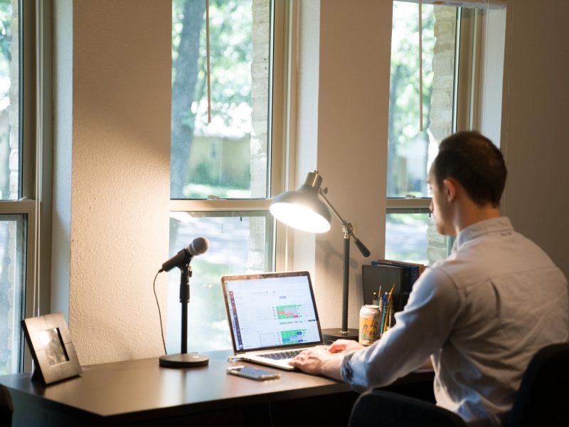 man in white dress shirt sitting on chair using laptop computer